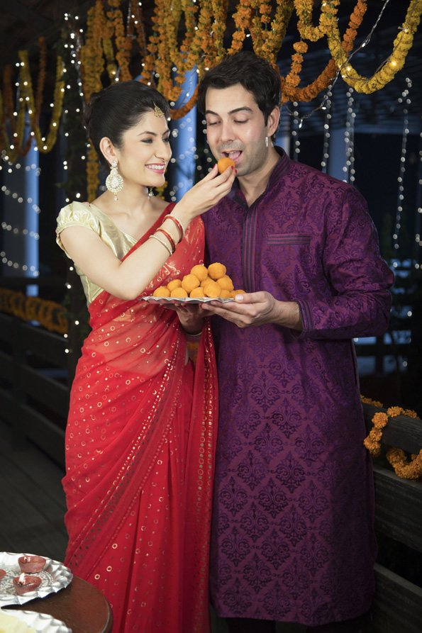 attractive young couple sharing diwali sweets