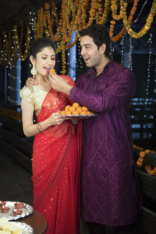 attractive young couple sharing diwali sweets
