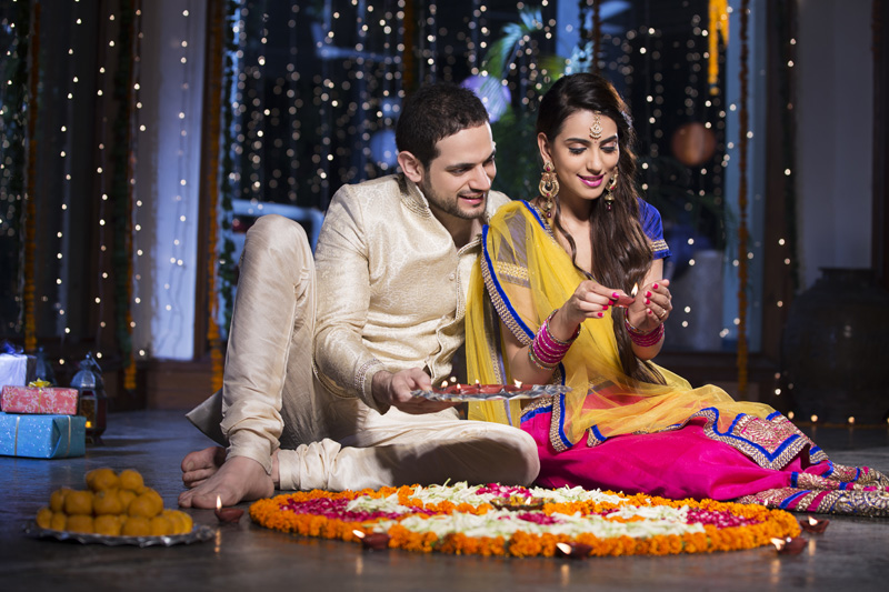 couple sitting and making rangoli on diwali