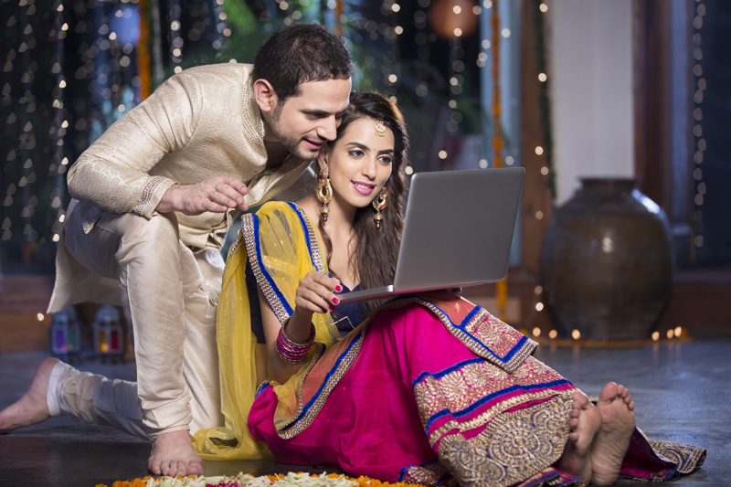 couple in traditional wear sitting with laptop