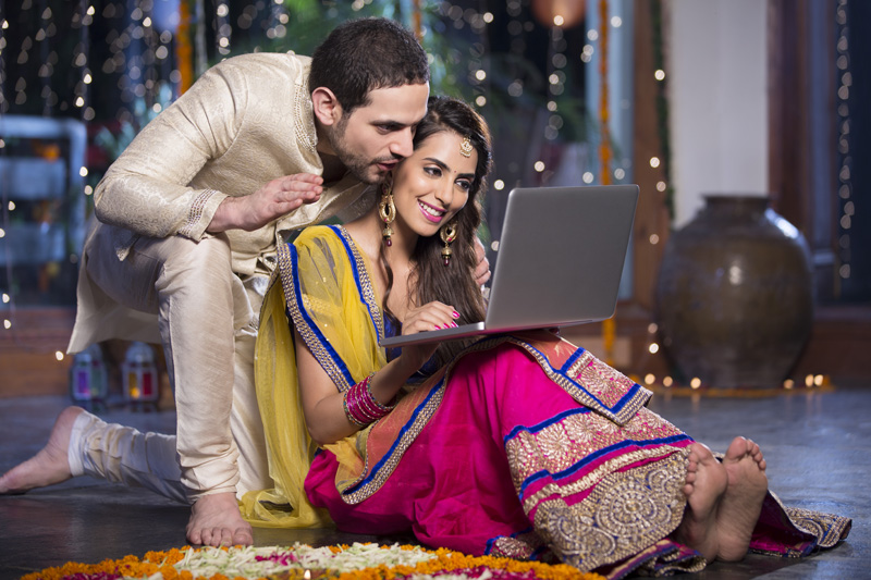 couple in traditional wear sitting with laptop