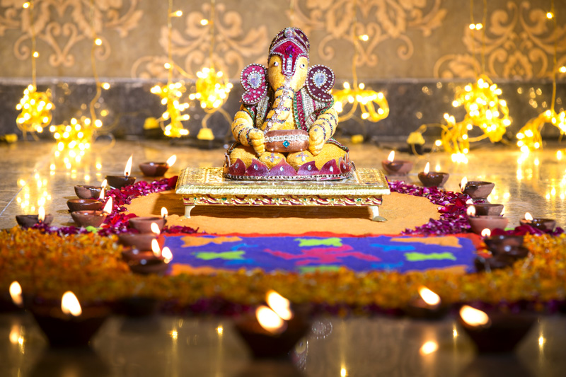 beautiful idol of ganesh placed against bright lights on diwali