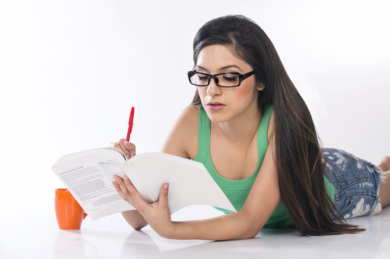 front view of a young teenage girl holding a pencil and a book