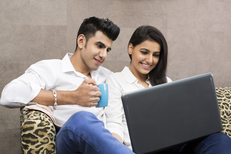man drinking coffee while woman browsing in laptop