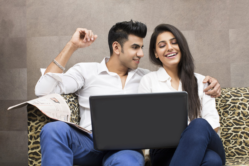 couple smiling while browsing in laptop