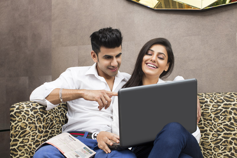couple on couch browsing in laptop