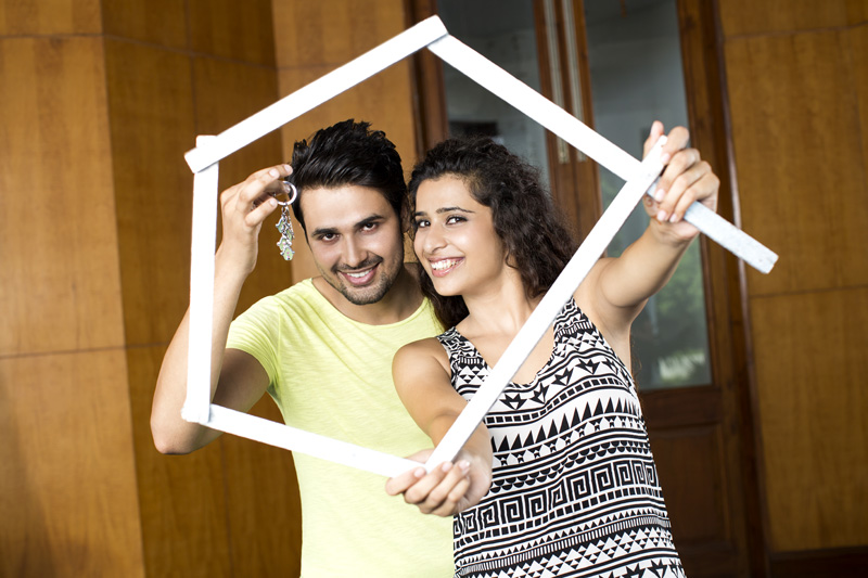 man showing house key while woman holding frame