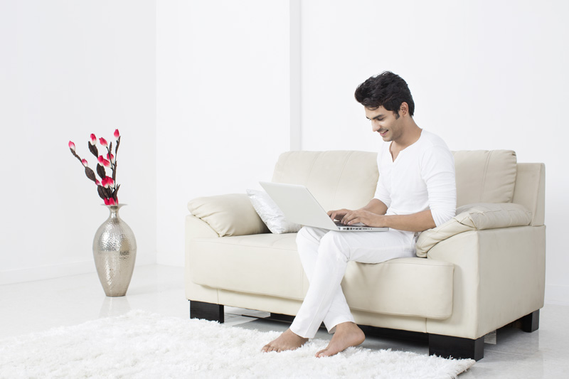 man on couch working on laptop