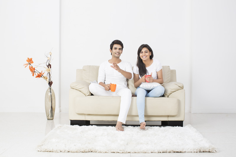 couple conversing while having coffee on couch