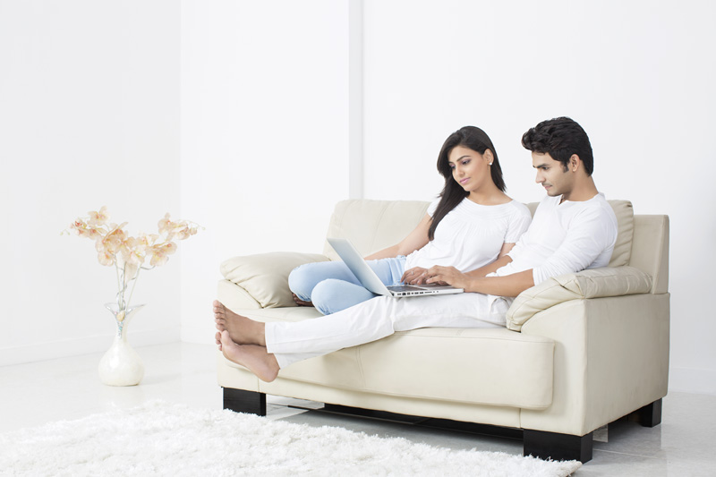 couple browsing in laptop while sitting on couch