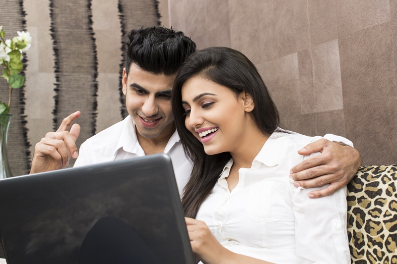 young couple having fun time while browsing in laptop