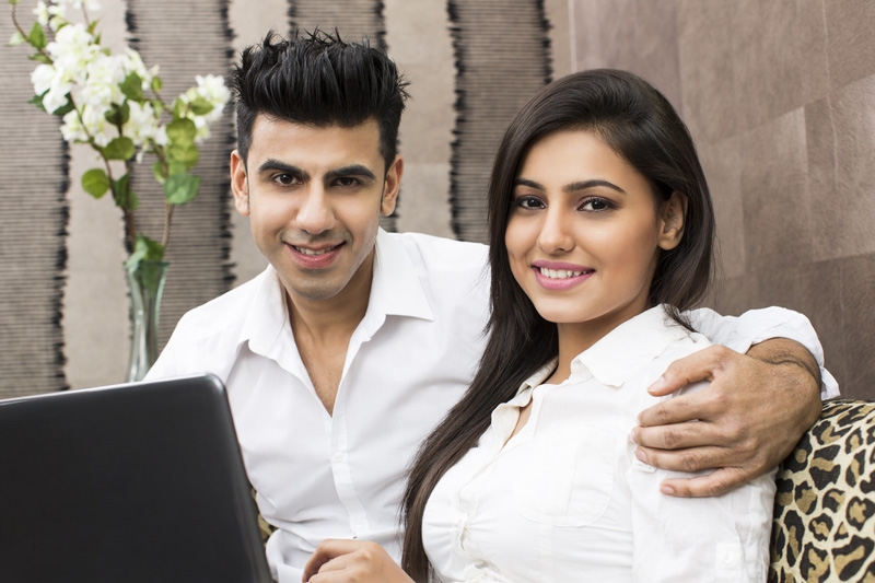 young couple with laptop posing for the camera 