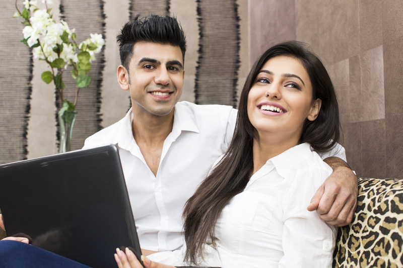 couple at home smiling and posing with laptop