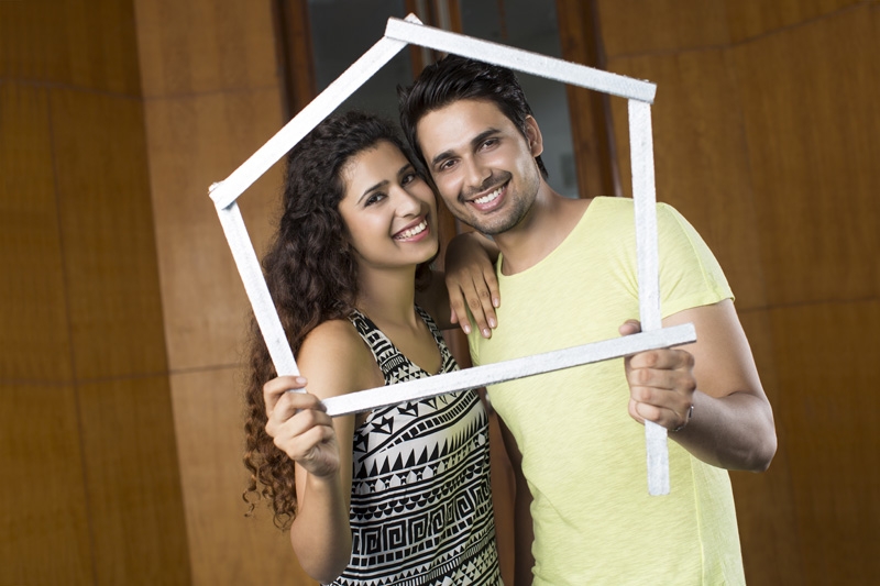 couple posing with house shaped frame