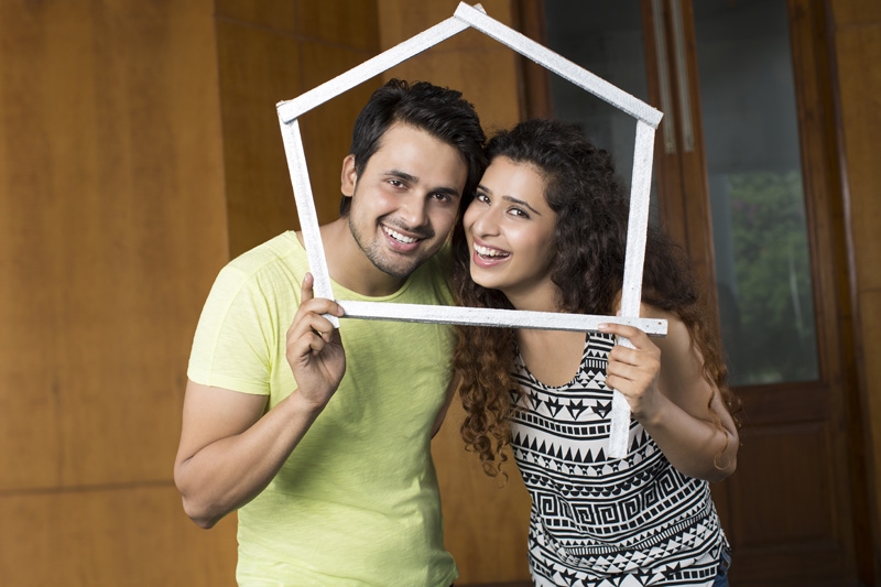 couple posing with house shaped frame