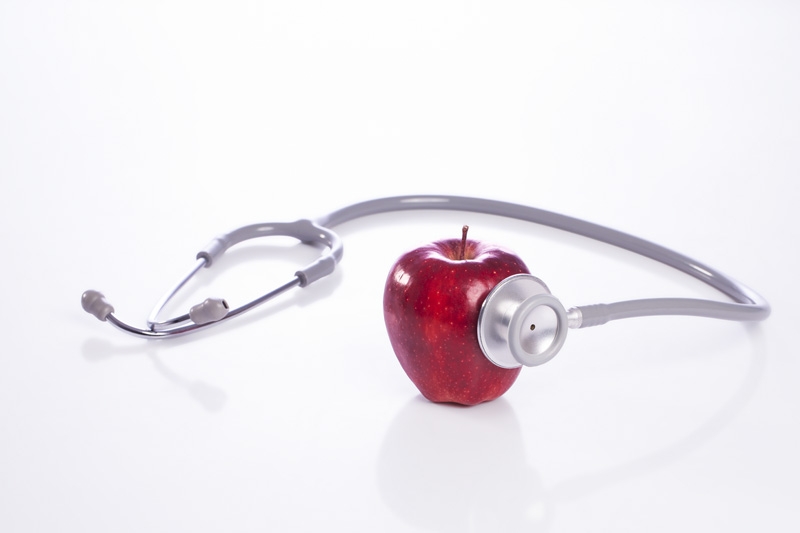 red apple with stethoscope against white background