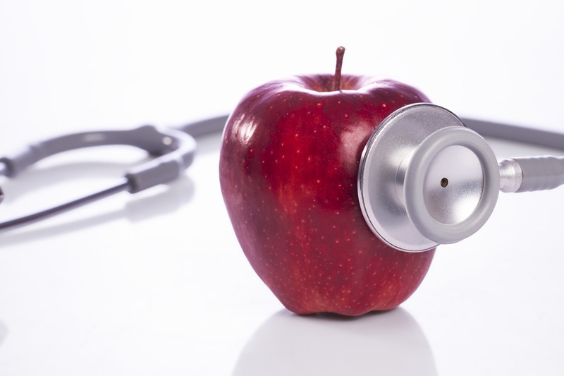 red apple with stethoscope against white background