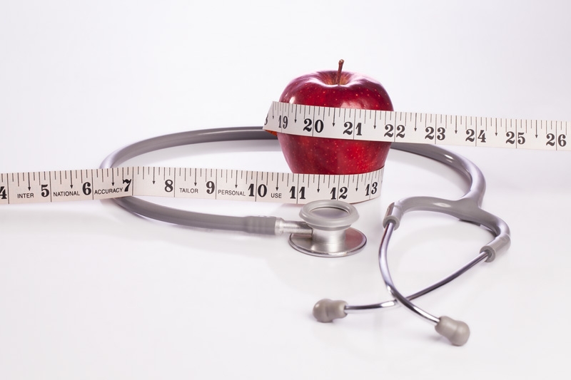 red apple wrapped with a tape and a stethoscope