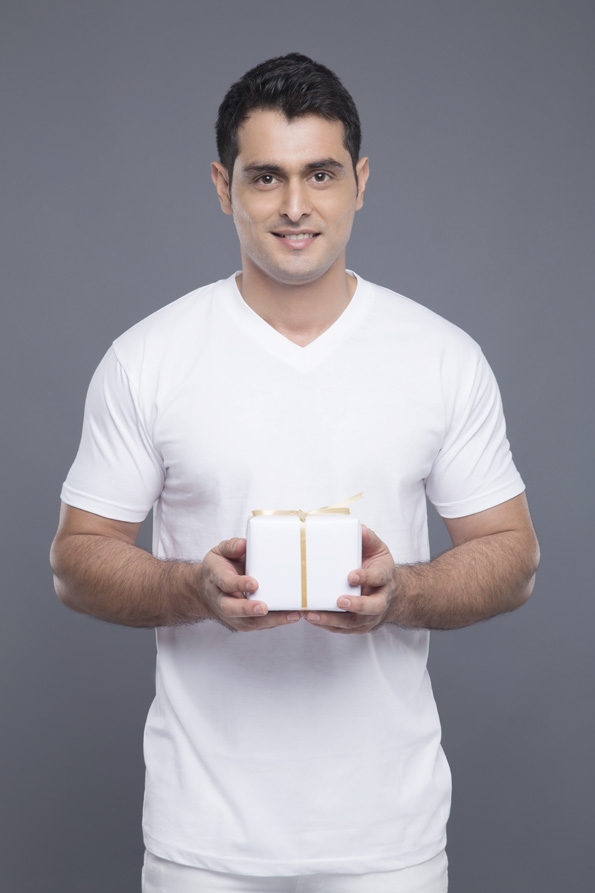 man in white clothing posing with a gift