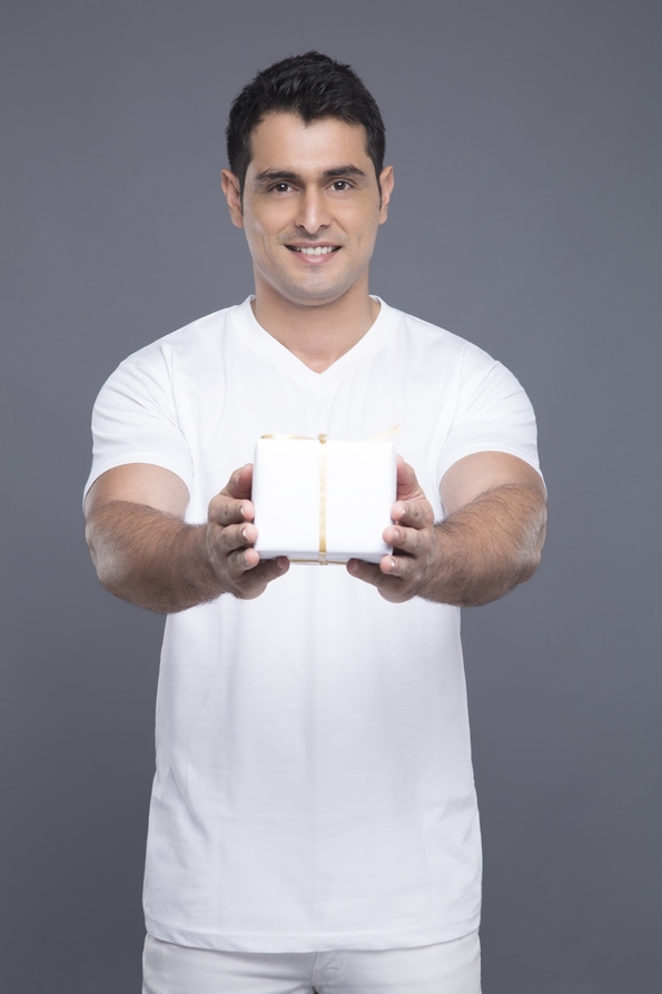 man in white clothing posing with a gift