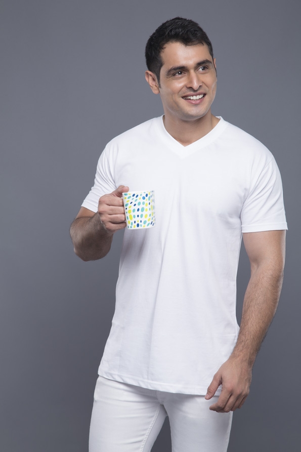 man in white clothes posing with a coffee mug