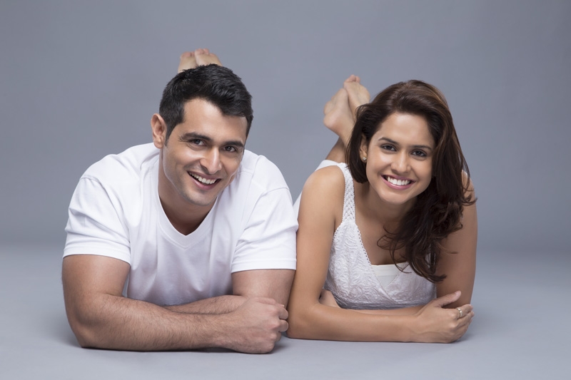 attractive young couple smiling at the camera on a white background
