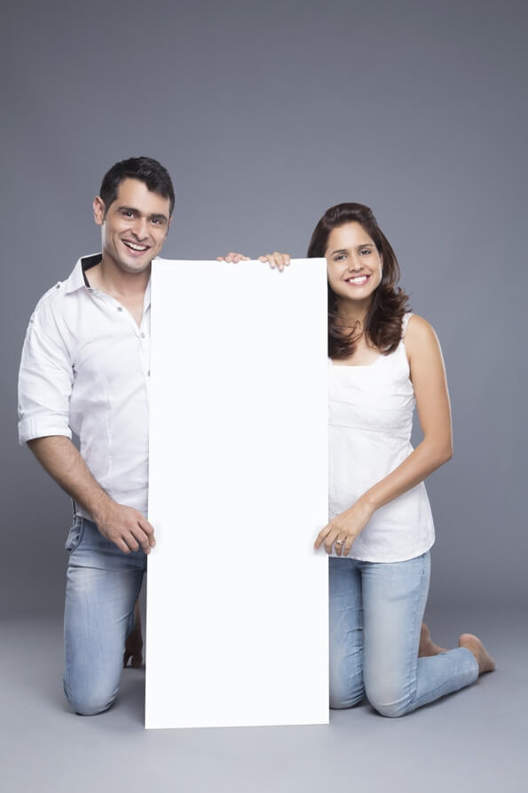 young couple holding a blank poster