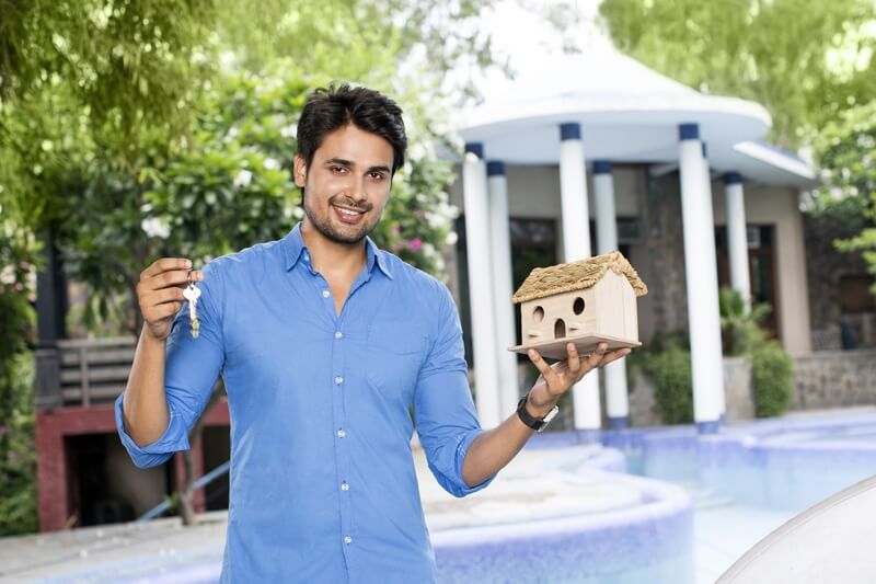 man posing with a home miniature outside villa