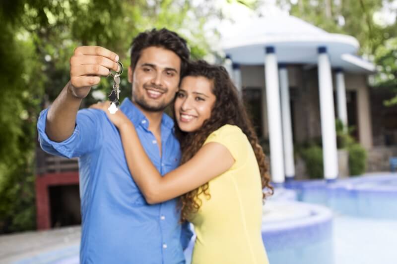 couple showing home keys outside the villa