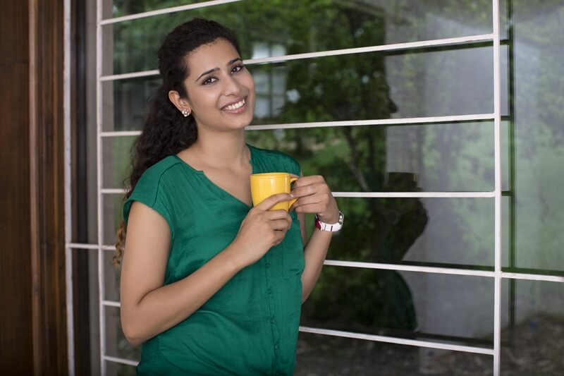 attractive young woman on a balcony enjoying morning with a cup of cof
