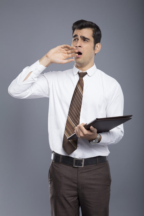 professionally dressed man standing with a file and yawning