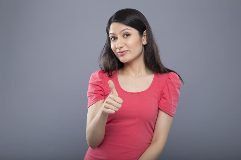 portrait of young woman showing thumbs up sign