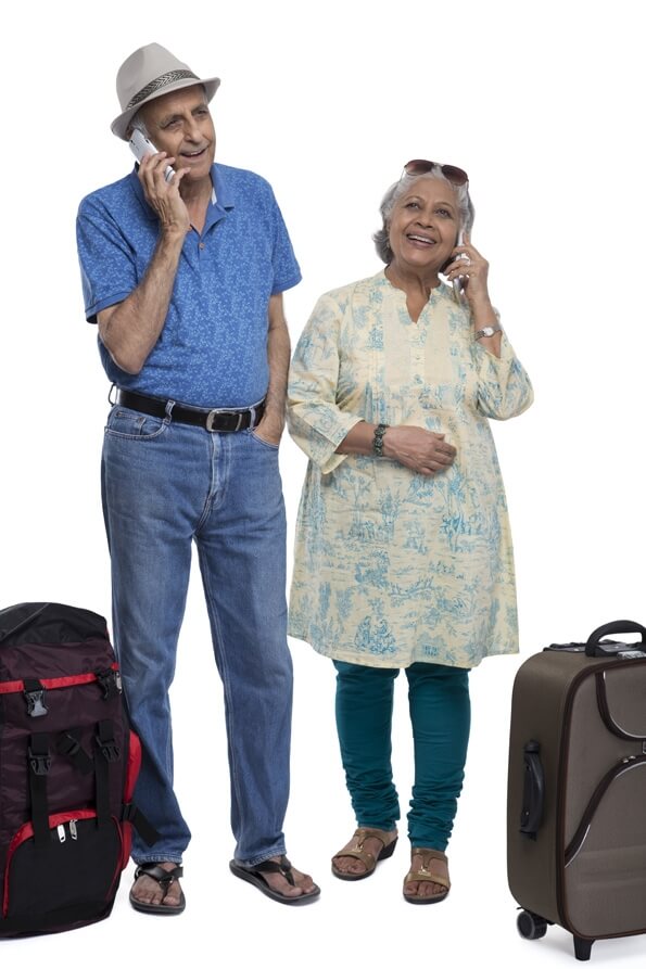 old couple with travelling bags and talking on phone 