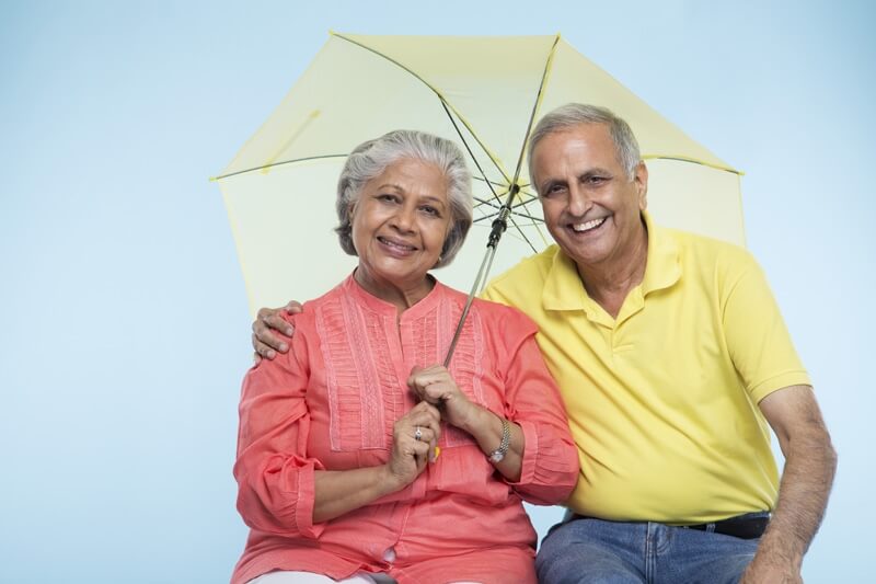 old couple posing with yellow coloured umbrella 