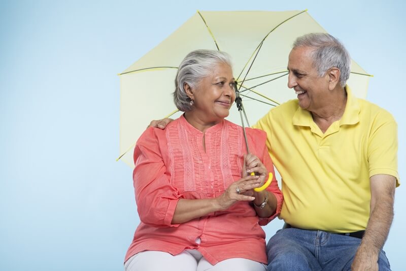 old couple posing with yellow coloured umbrella 