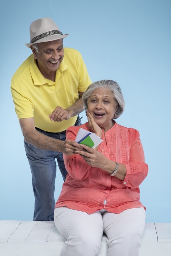 old couple posing with air tickets 