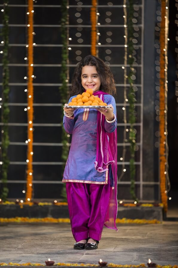 sweet girl holding a thali of laddu on diwali