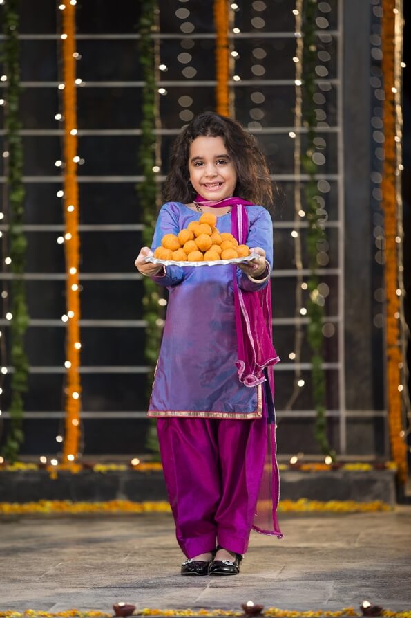 sweet girl holding a thali of laddu on diwali