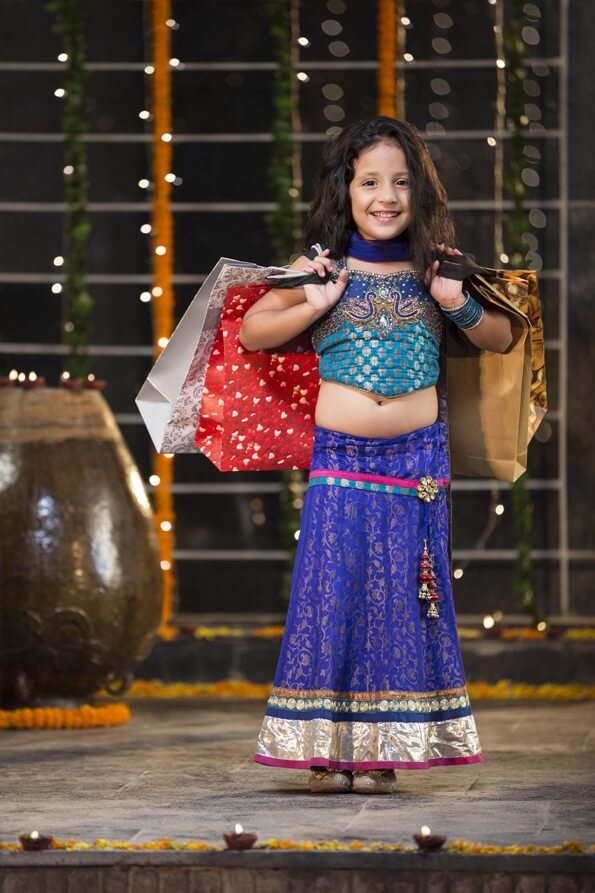 cheerful little girl carrying shopping bags on diwali
