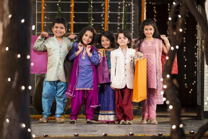 five small kids dressed in traditional outfit holding shopping bags