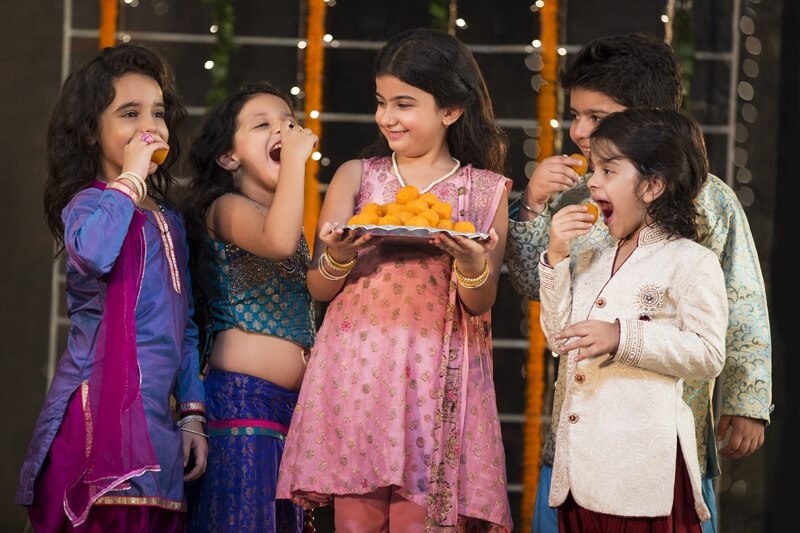 group of kids eating laddu on diwali