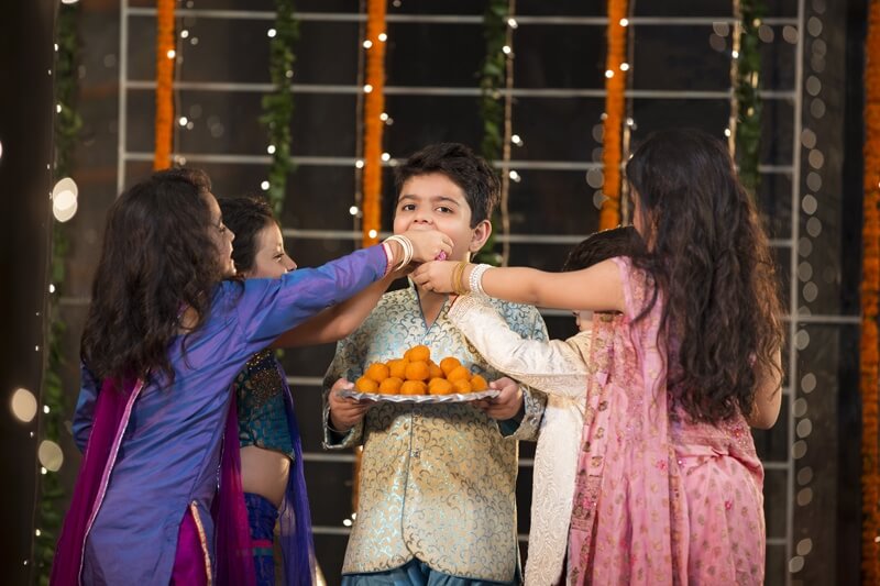 kids offering laddu to their friend