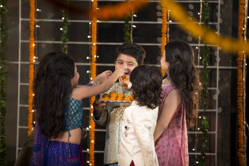 kids offering laddu to their friend