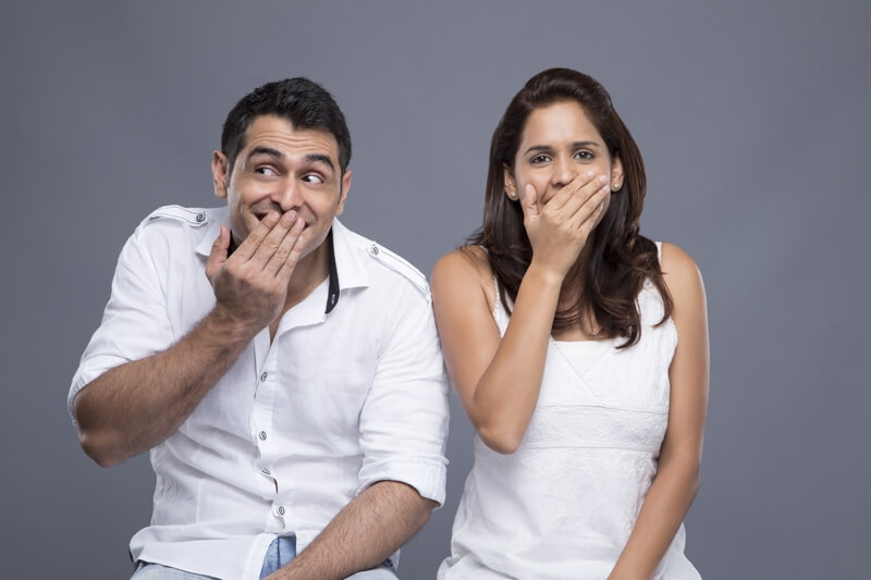 couple with mouth covered by hands 