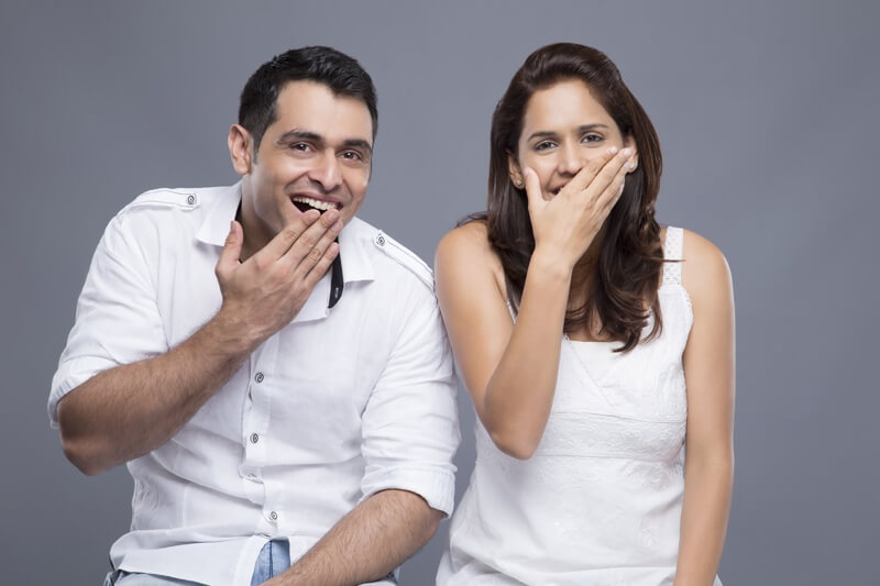 couple with mouth covered by hands 