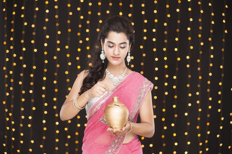 woman in ethnic wear posing with piggy bank