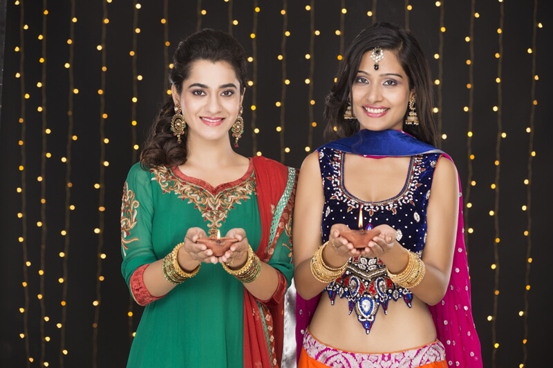 girls in indian wear posing with diyas 