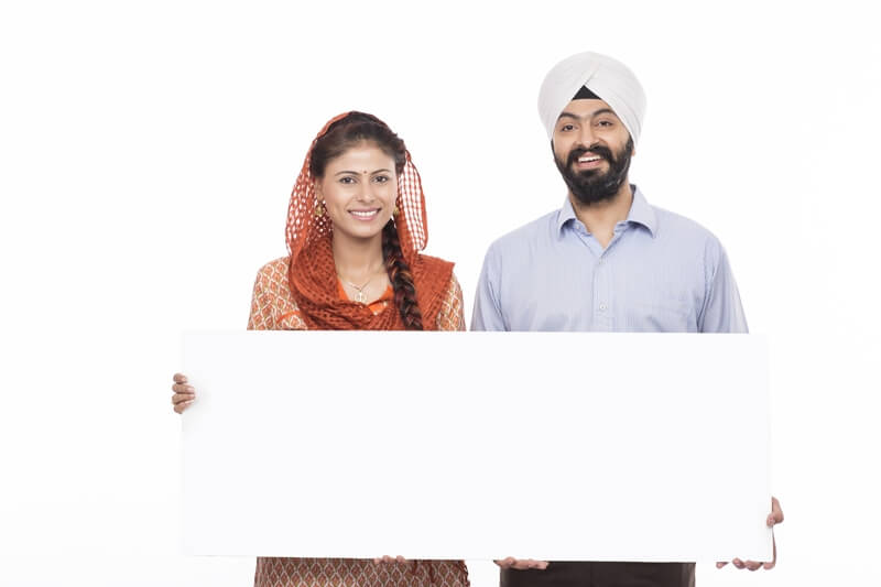 sikh couple standing with a message board 
