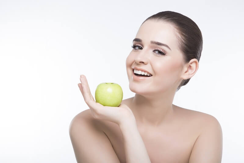 girl showing green apple while posing for the camera