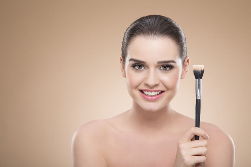 girl posing with make up brush and smiling